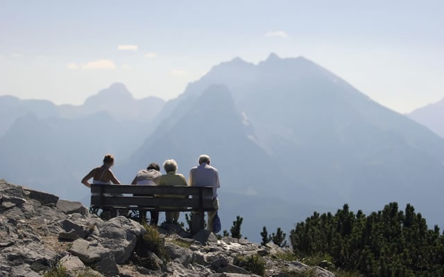 personen op bankje met uitzicht op bergen